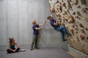 Boulderer an Kippwand mit Holzgriffen in Kletterhalle, Boulderhalle,